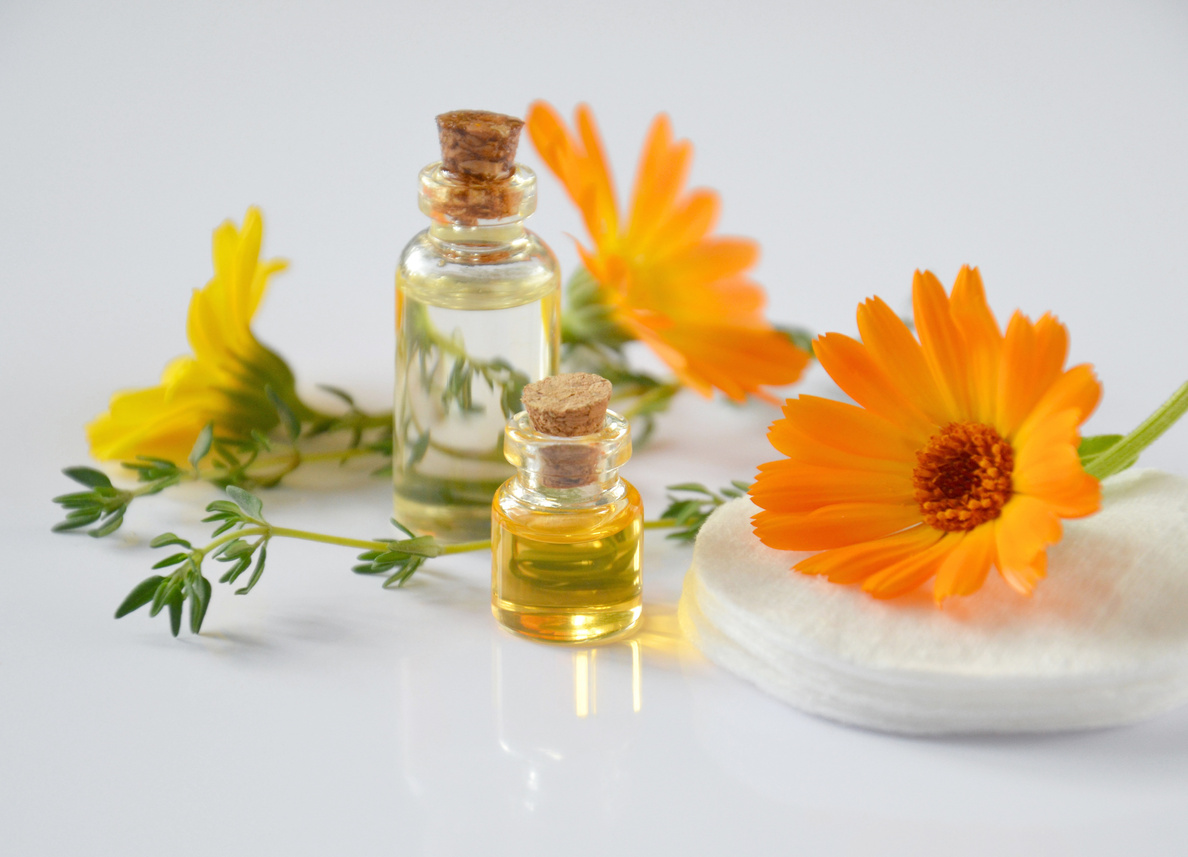 Essential Oil Bottles and Calendula Flowers in Black Background