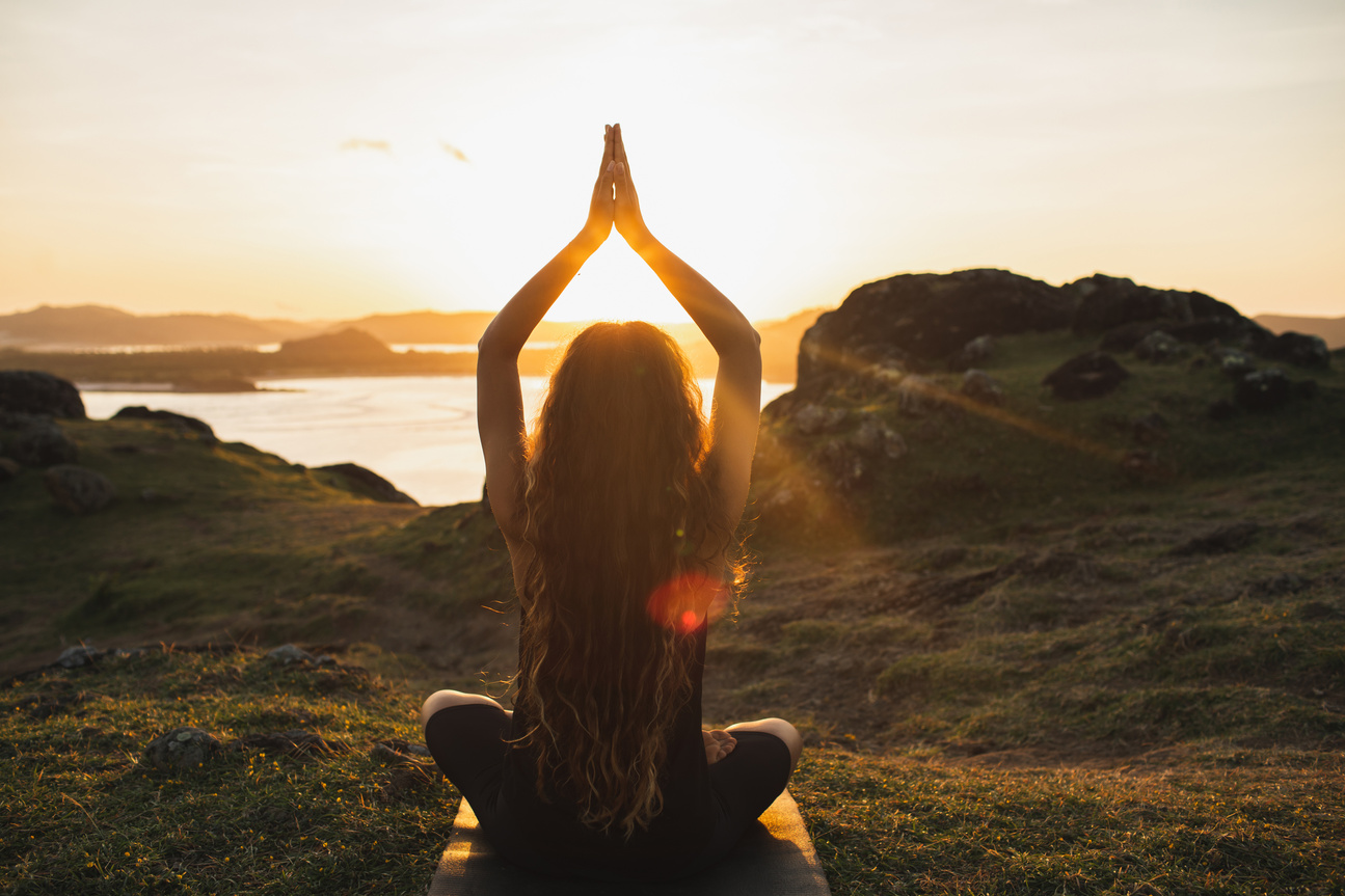 Young woman practicing yoga outdoors.  Spiritual harmony, introspection and well-being concept. Landscape background